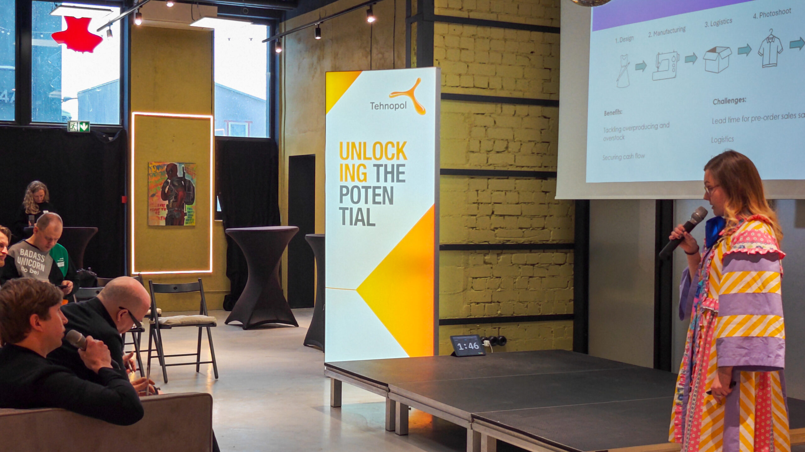 woman giving a pitch in front of an audience and a jury.